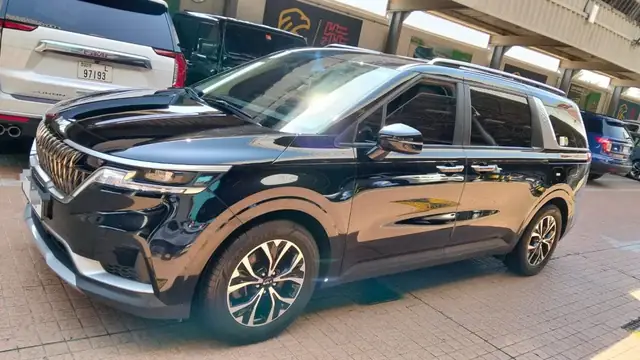 Black Kia Carnival front view at a petrol station