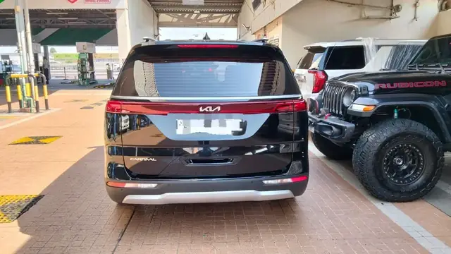 Black Kia Carnival rear view at a petrol station