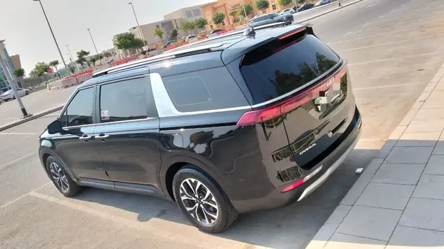 Black Kia Carnival rear view on a Dubai street